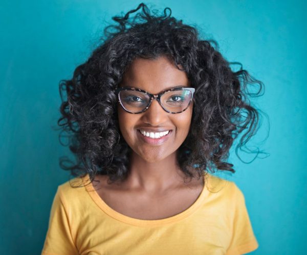 mulher jovem de pele negra sorrindo e com óculos de grau