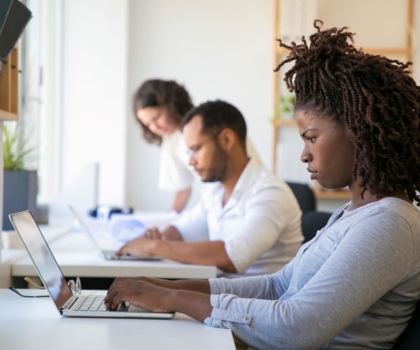 mulher negra franzindo a testa e trabalhando em frente ao computador.