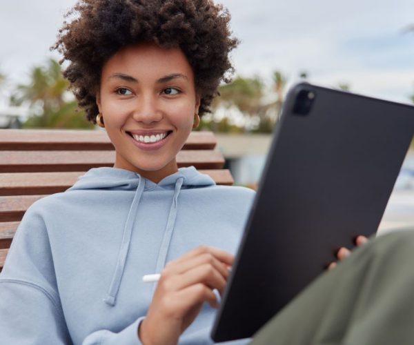 mulher negra vestida com moletom cinza segurando um tablet